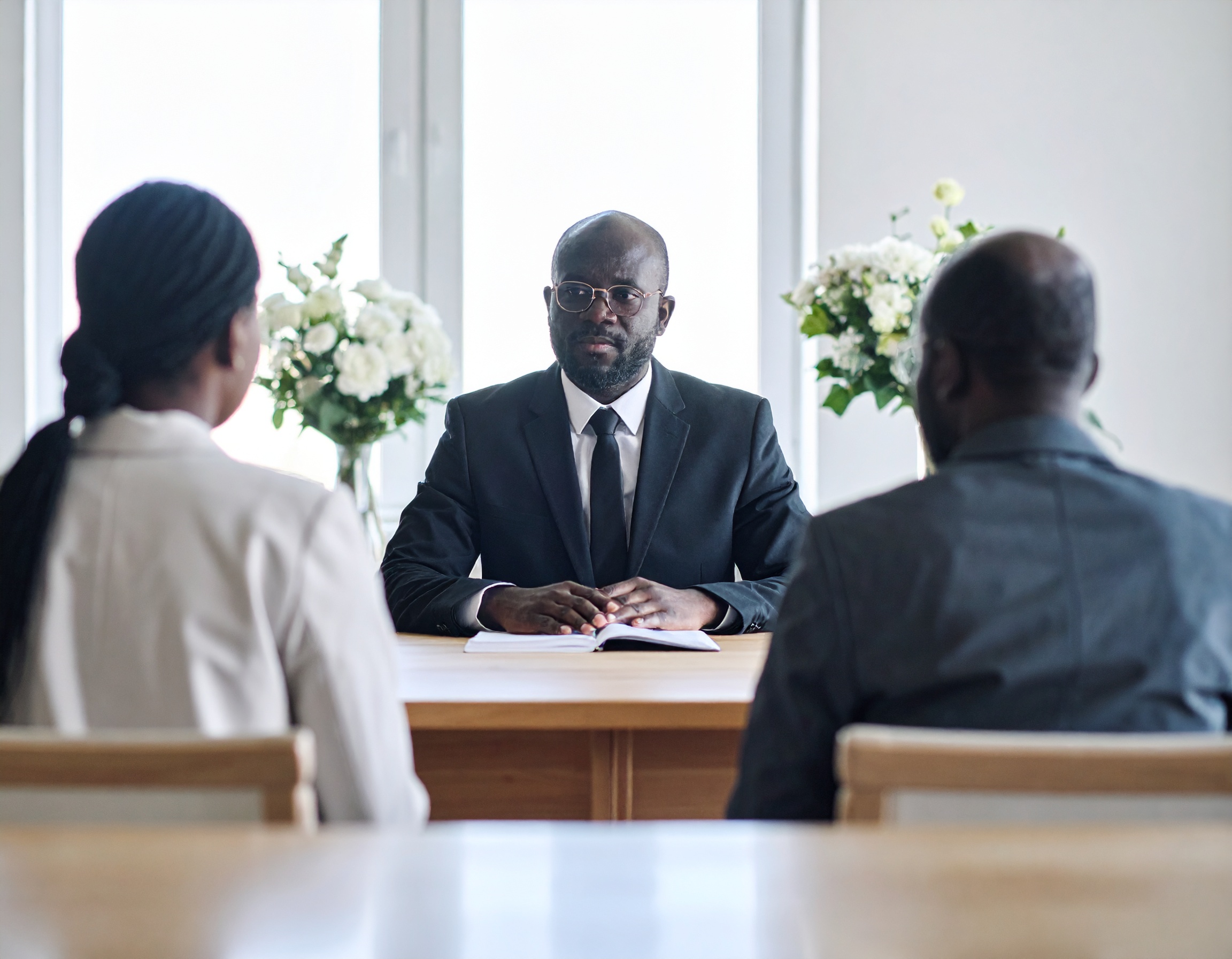 Firefly_single funeral director sitting behind a desk facing the family sitting in front of t 560560